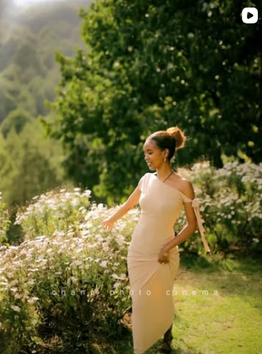 Woman in beige dress posing in a lush green floral garden Addis Ababa